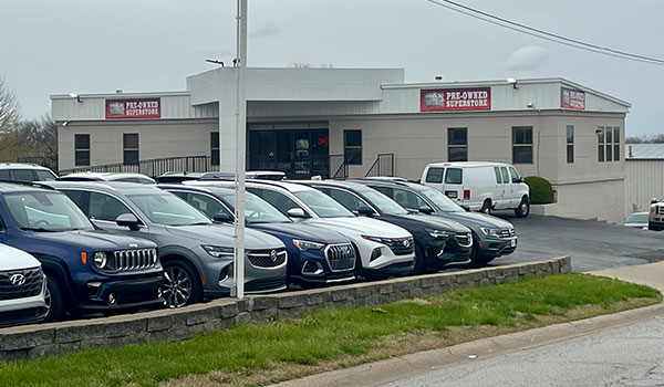 photo of front of building with car lot.